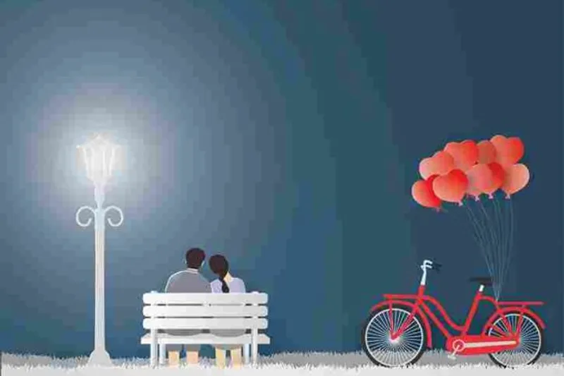 Two people sit close together on a bench beside a bicycle carrying heart-shaped balloons